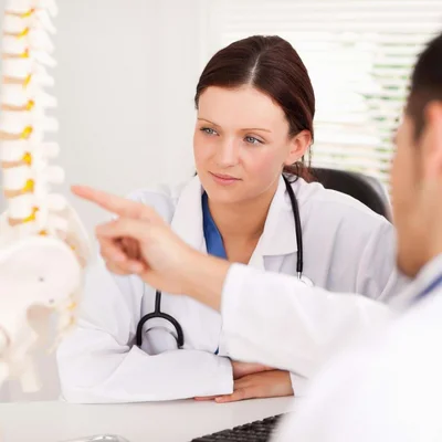 Ärztin und Arzt betrachten Wirbelsäulenmodell